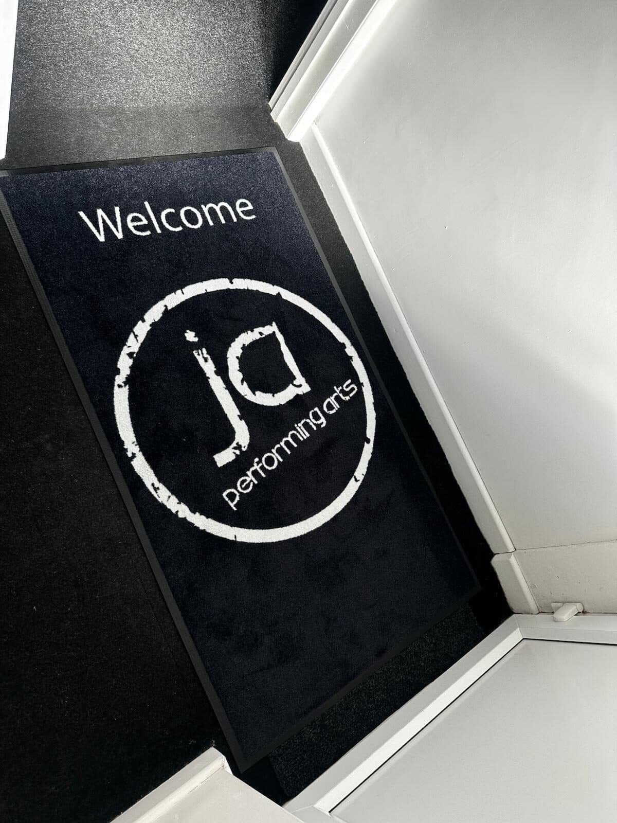 JA Performing Arts branded welcome mat at the studio entrance